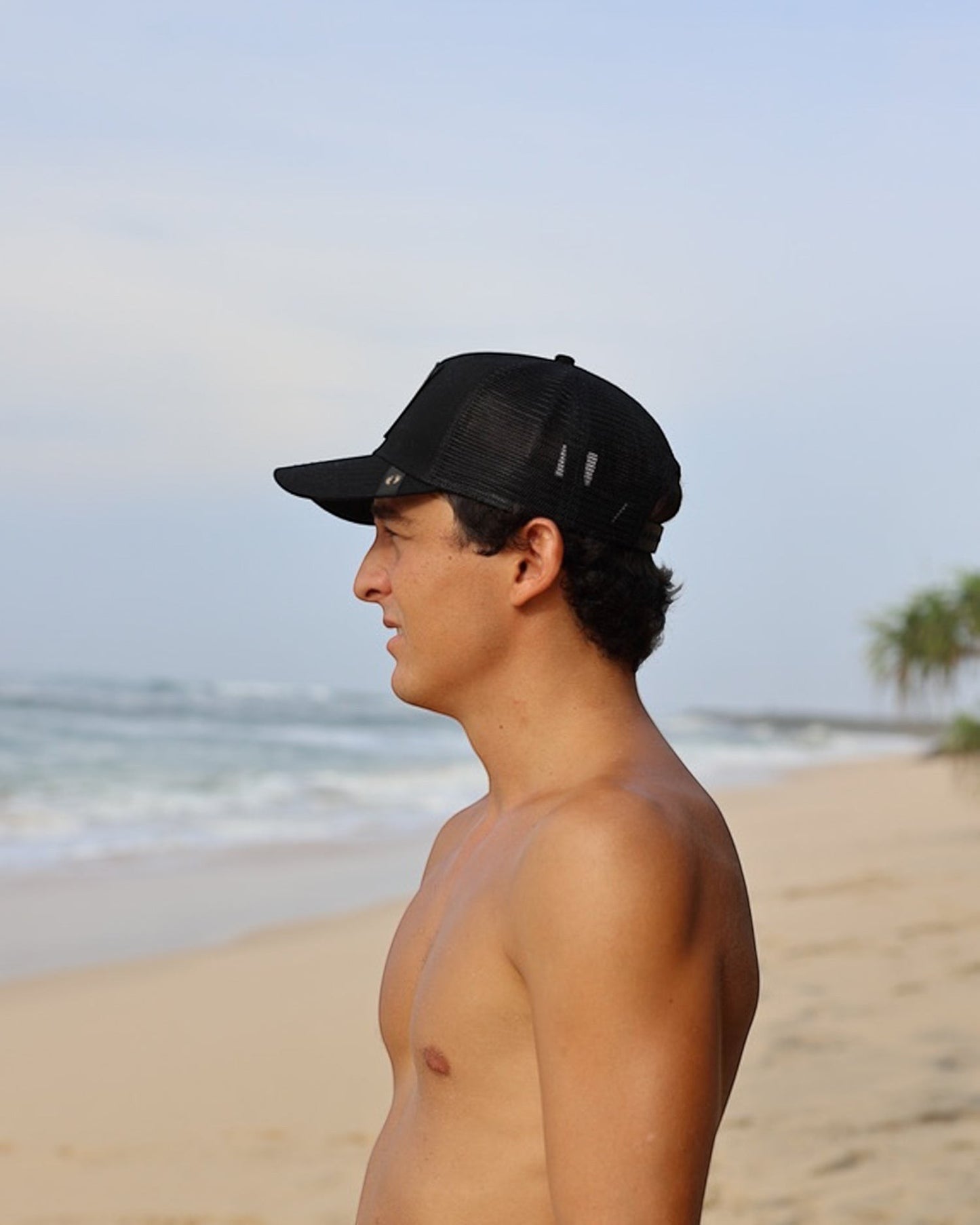 Hang Ten black trucker cap with mesh back and embroidered logo, perfect for surfing.