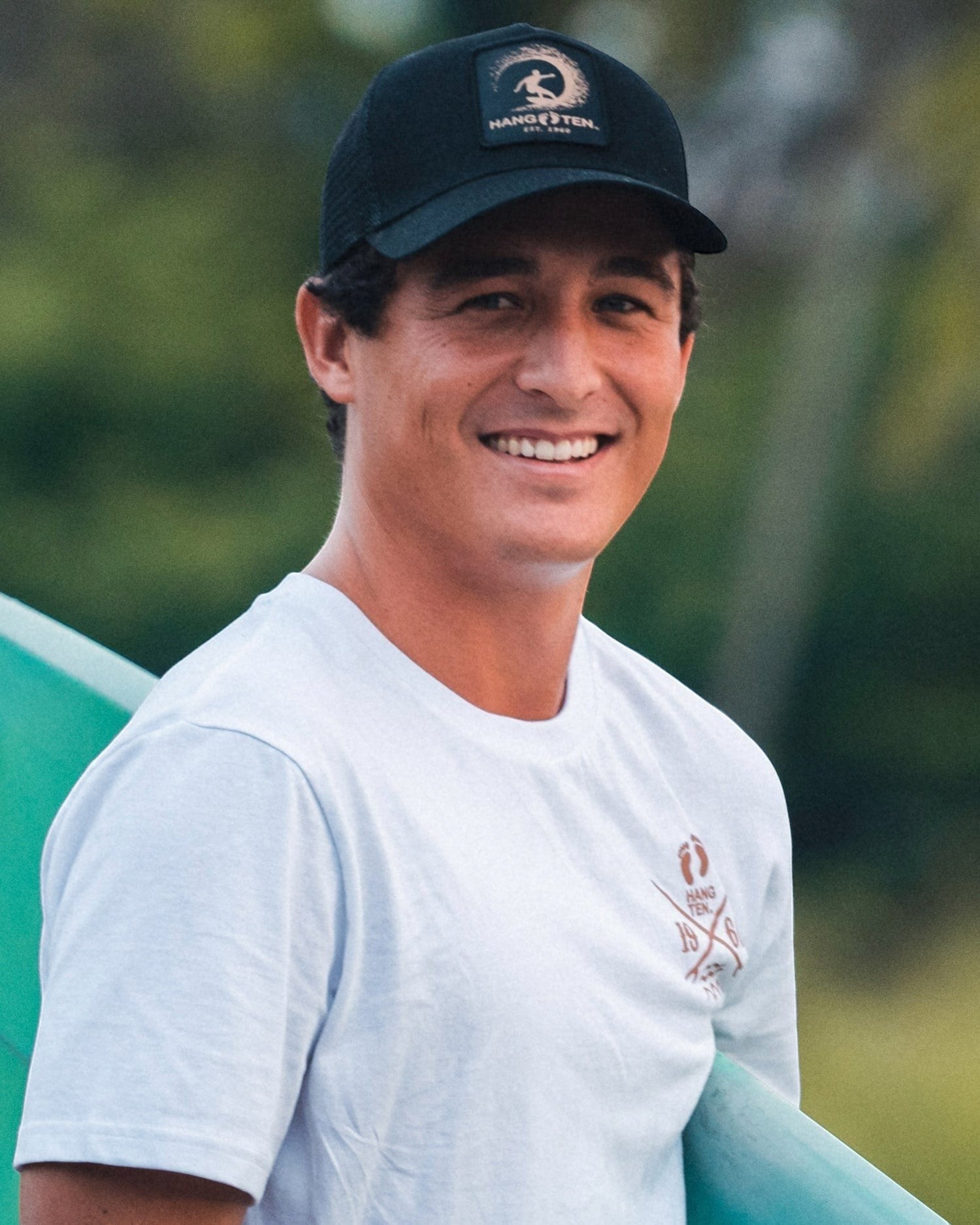 Hang Ten black trucker cap with embroidered logo patch and adjustable snapback. Cotton and polyester blend.